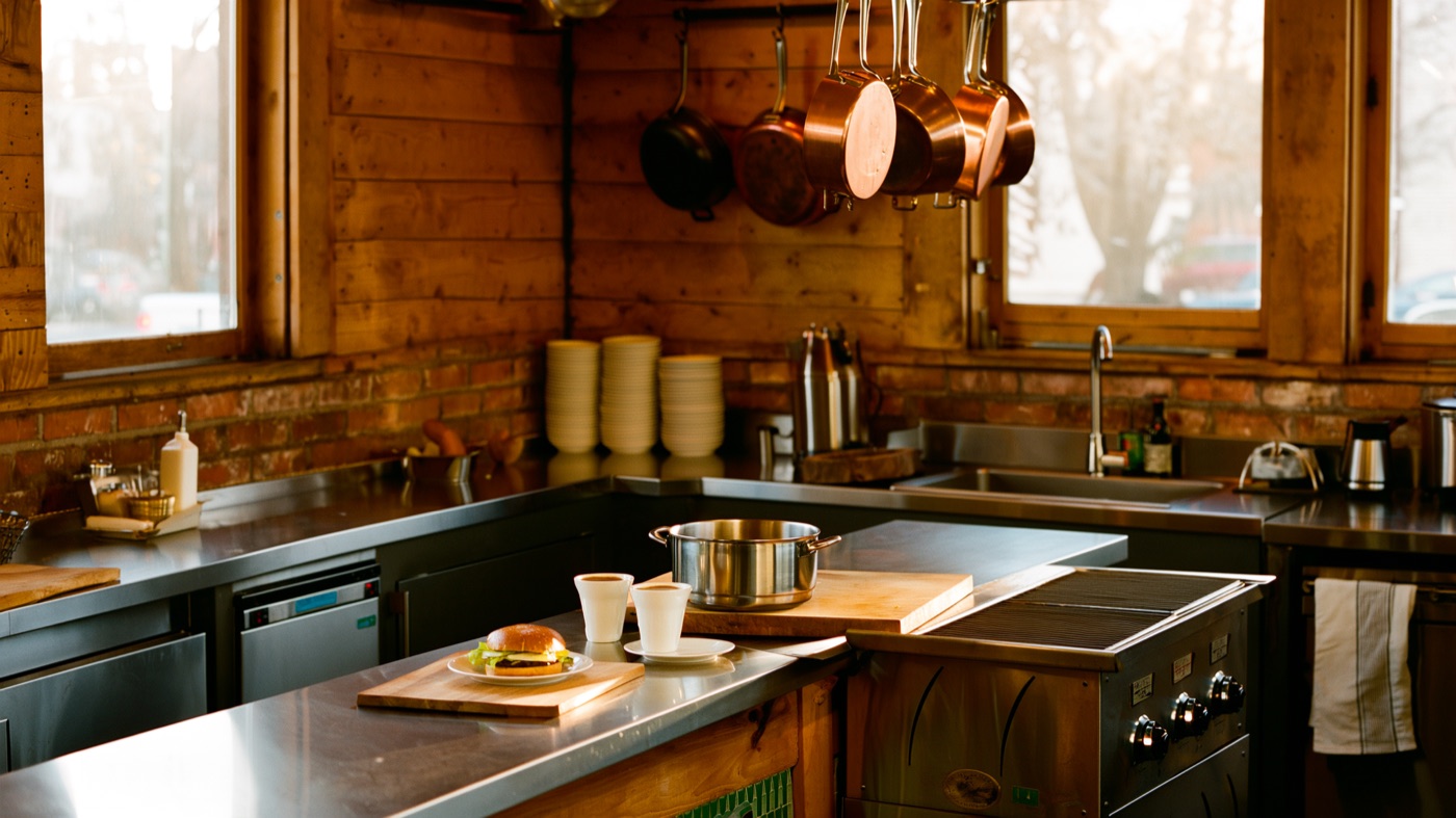 Inside The Gastropig kitchen — copper pans, a breakfast sandwich on the pass and warm morning light